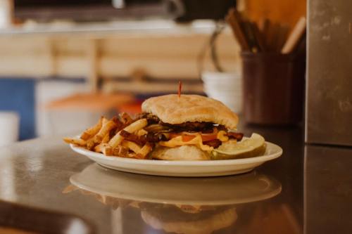 A plate with a burger topped with cheese, lettuce, and tomato, accompanied by fries and a pickle slice.