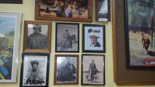 A collage of framed black-and-white photographs featuring cowboys and soldiers on a wall.