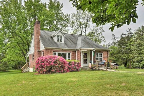 A charming brick house surrounded by lush greenery and blooming azaleas, set in a peaceful outdoor environment.