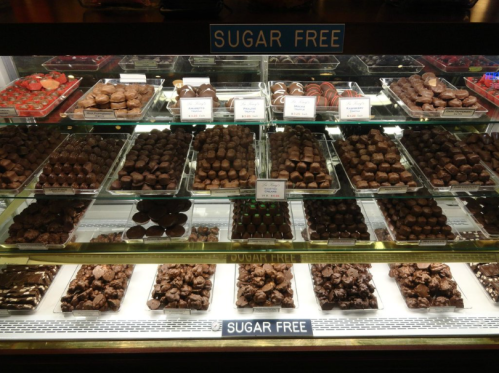 Display case filled with various sugar-free chocolates and confections, neatly arranged on glass shelves.