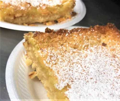 Two slices of cake on white plates, topped with powdered sugar and showing a moist, golden interior.