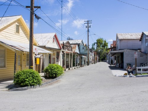 A quiet street in a small town, lined with colorful wooden buildings and clear blue skies above.