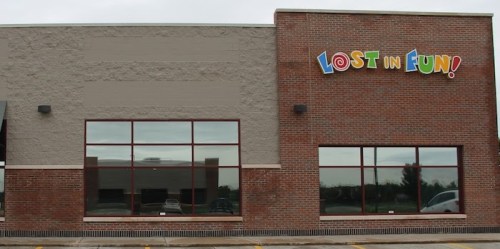 Exterior of a brick building with large windows and a colorful sign that reads "Lost in Fun!"