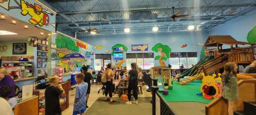 A colorful indoor play area with slides, climbing structures, and children playing in a lively, cheerful environment.