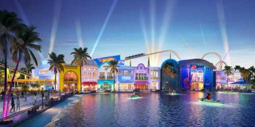 Colorful amusement park at dusk, featuring shops, a roller coaster, and palm trees reflected in the water.