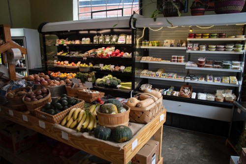 A vibrant market display featuring fresh fruits, vegetables, and various packaged goods on wooden tables and shelves.