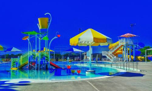 Colorful water slides and umbrellas around a swimming pool on a sunny day.