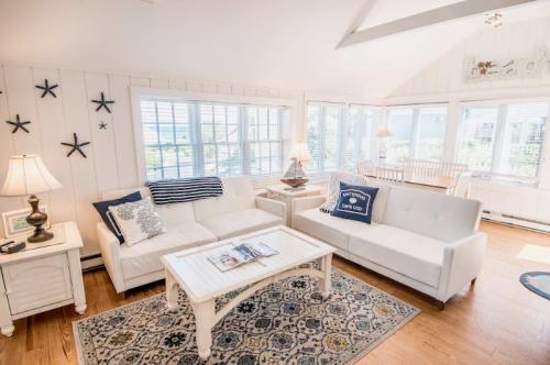 Bright, airy living room with white sofas, a coffee table, and large windows, decorated with nautical accents.
