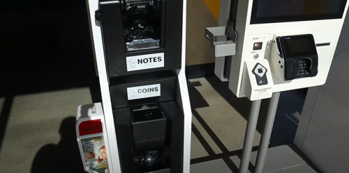 Self-service kiosk with a note and coin dispenser, alongside a payment terminal and informational pamphlet holder.