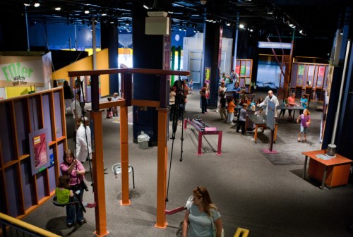 A vibrant science museum exhibit with interactive displays and visitors exploring various hands-on activities.