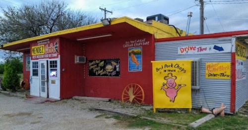 A colorful restaurant exterior with signs for catfish and pork chops, featuring a drive-thru and playful pig graphic.