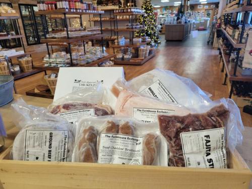 A wooden display holds various packaged meats, including chicken and beef, in a rustic store setting.