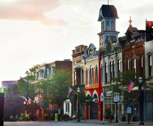 Historic buildings line a street, adorned with American flags, under a soft sunset glow.