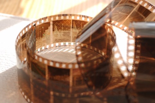 A close-up of a curled film strip, showcasing multiple frames with images, resting on a textured surface.