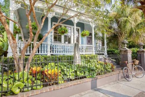 A charming house with a porch, surrounded by lush greenery and a bicycle parked nearby.