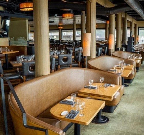 Interior of a modern restaurant featuring curved leather seating, wooden tables, and ambient lighting.