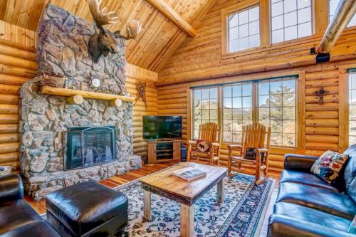 Cozy log cabin interior with a stone fireplace, wooden furniture, and large windows showcasing a mountain view.