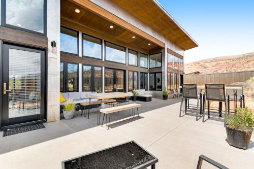 Modern outdoor patio with seating, large windows, and desert landscape in the background. Bright and inviting atmosphere.