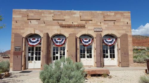 Historic building with three arched doors, adorned with red, white, and blue bunting, set against a clear blue sky.