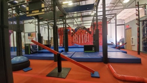 A vibrant indoor obstacle course with various climbing structures, mats, and equipment for training and fitness activities.