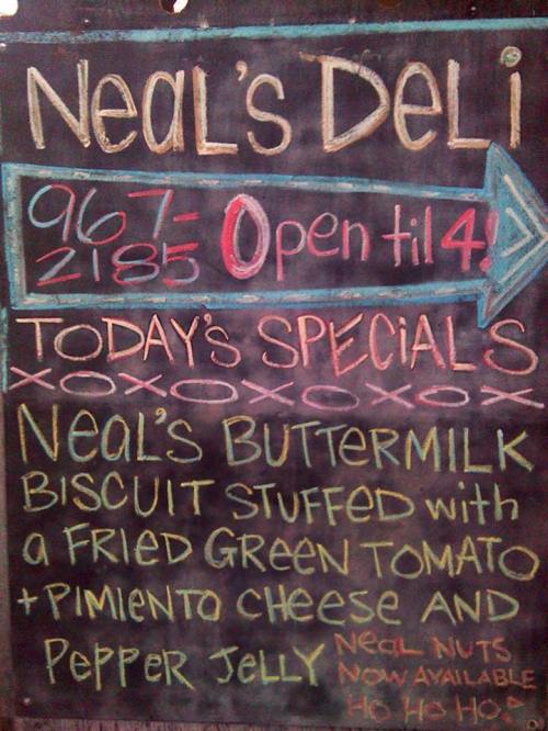 Chalkboard sign for Neal's Deli with specials: buttermilk biscuit with fried green tomato, pimento cheese, and pepper jelly.