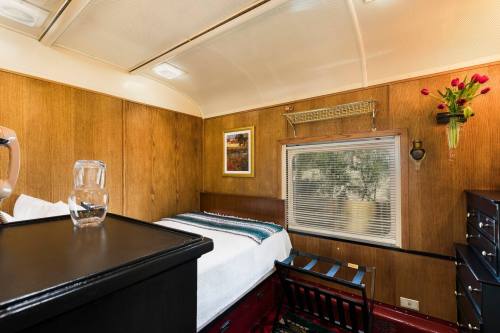 Cozy room with wooden walls, a bed, a chair, and a window with a vase of flowers on the wall.
