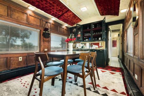 A cozy dining area with a wooden table, chairs, and a bar, featuring rich wood paneling and red accents.