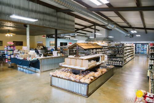 Interior of a grocery store featuring shelves of products, a bakery display, and a rustic metal decor.