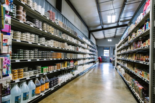 A wide aisle in a store lined with shelves filled with various products, including jars and containers.