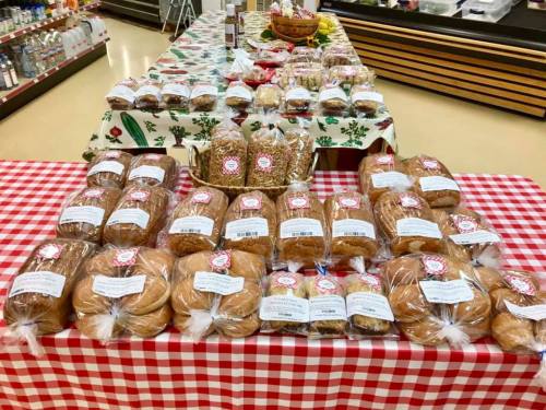 A table covered with a red and white checkered cloth, displaying various bags of baked goods and snacks.
