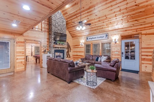 Cozy living room in a wooden lodge with a stone fireplace, comfortable seating, and a welcoming atmosphere.