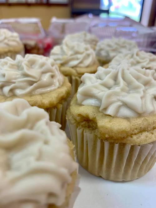 Close-up of freshly baked cupcakes with creamy frosting, arranged neatly on a table.