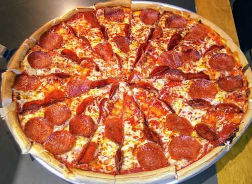 A large pepperoni pizza sliced into 16 pieces, with a golden crust and melted cheese.