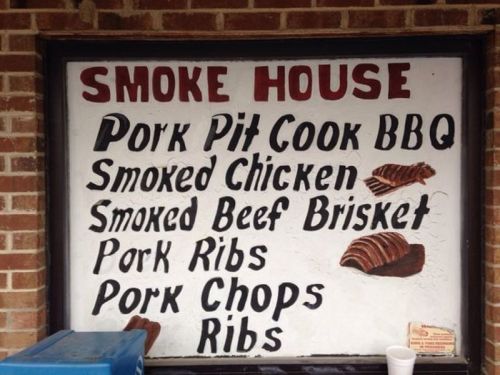 Sign for a smokehouse featuring menu items: BBQ, smoked chicken, beef brisket, pork ribs, pork chops, and ribs.