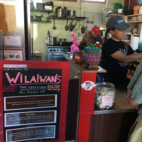A cozy café interior with a menu board, staff at the counter, and colorful decorations.