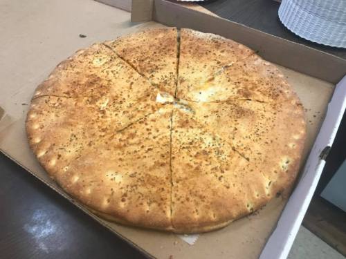 A large, golden-brown pizza with a crispy crust, cut into eight slices, in a pizza box.