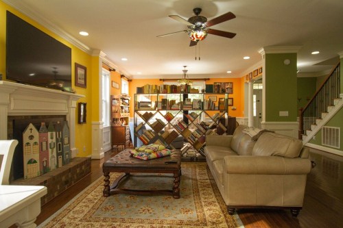 Cozy living room with a beige sofa, colorful walls, a large bookshelf, and a decorative coffee table.