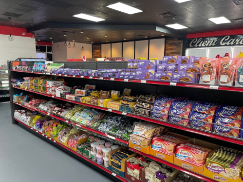 A colorful display of various snacks and candies on shelves in a modern store interior.