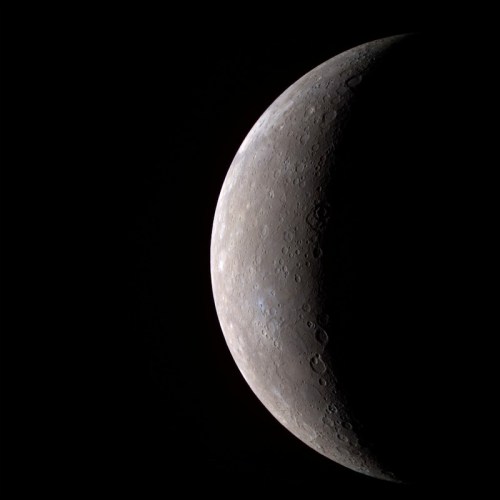 Close-up view of Mercury's surface, showcasing its craters and rugged terrain against a dark background.