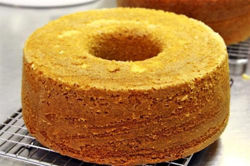 A freshly baked round cake with a hole in the center, cooling on a wire rack.