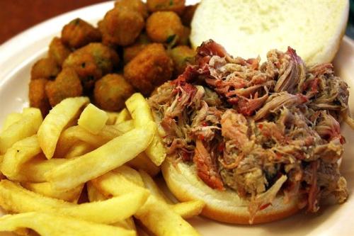 A plate featuring a pulled pork sandwich, French fries, and fried okra.