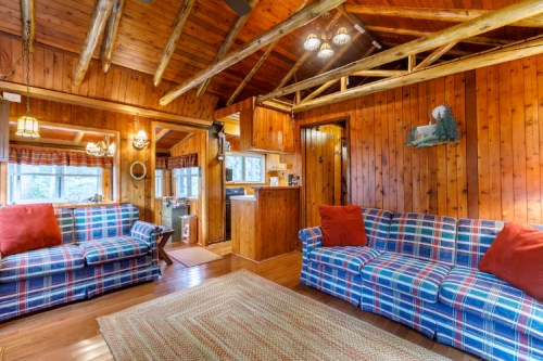 Cozy cabin interior with wooden walls, plaid sofas, and a warm, inviting atmosphere.