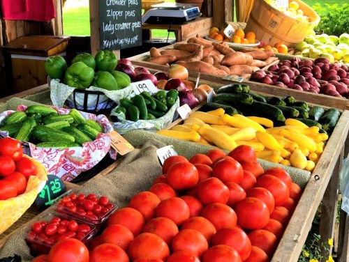 A vibrant farmers' market display featuring various fresh vegetables and fruits, including tomatoes, peppers, and squash.