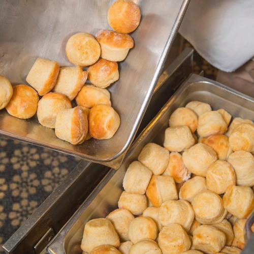 A metal tray filled with golden-brown biscuits, some spilling out onto a surface.