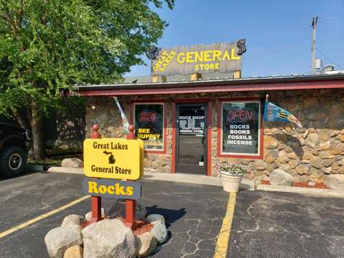 A stone-front general store with a sign reading "Great Lakes General Store" and colorful flags outside.