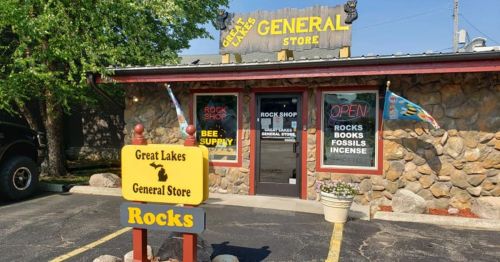 A stone building with a sign reading "Great Lakes General Store" and "Open," featuring a rock shop and various supplies.