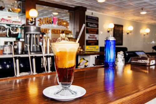 A frothy root beer float in a glass on a wooden counter, with a vintage soda shop backdrop.