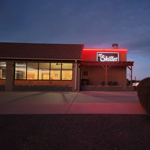 Exterior of a restaurant called "The Skillet," illuminated by red neon lights at dusk.