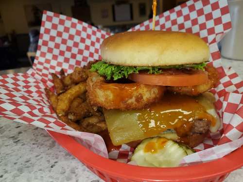 A delicious burger with lettuce, tomato, and cheese, served with crispy fries in a red checkered basket.