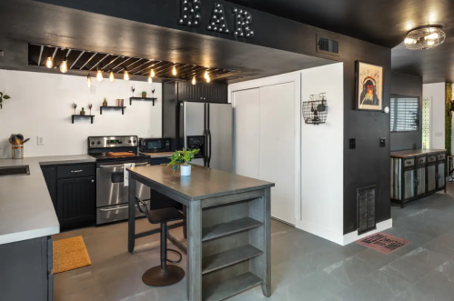 Modern kitchen with a bar area, stainless steel appliances, and a sleek black and white design.
